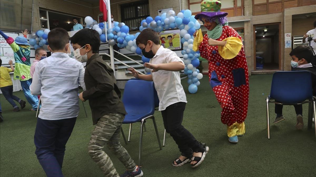 Un payaso juega con los estudiantes durante la ceremonia de apertura de la escuela Hashtroudi, en Teherán. Irán abrió el nuevo año escolar después de casi siete meses de cierre, ya que muchos expresaron su preocupación por un posible aumento de infecciones del Covid-19.