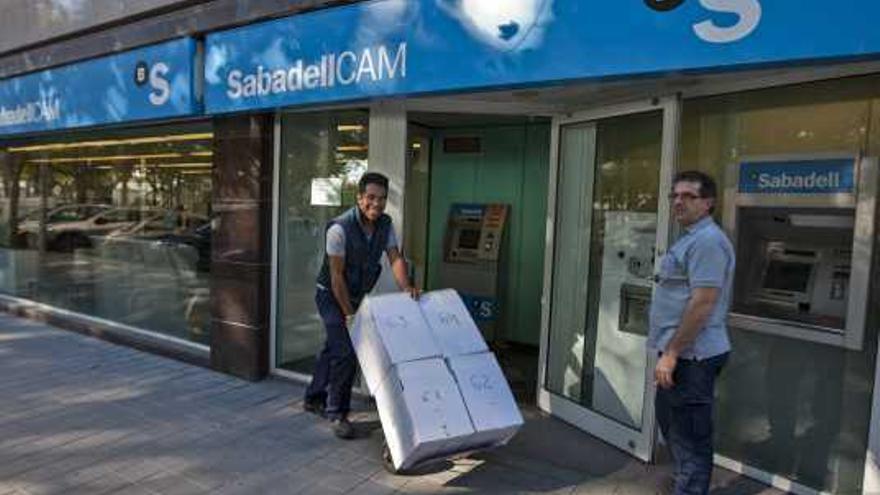 Operarios desmontando una oficina del SabadellCAM para su clausura.