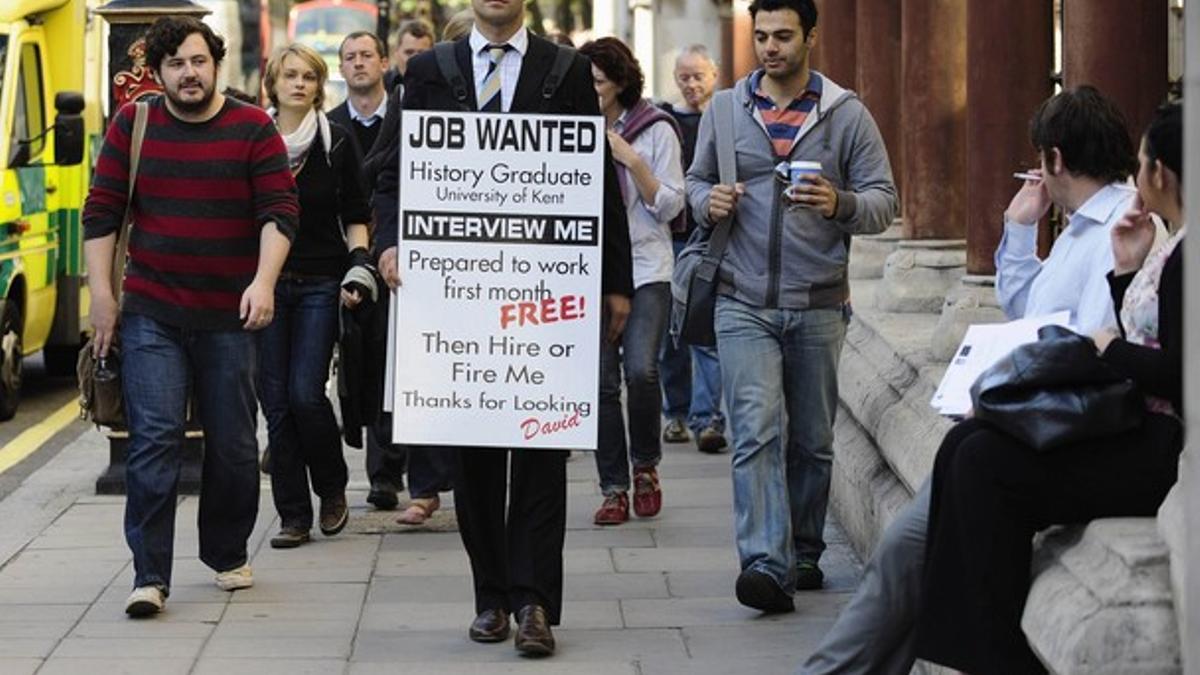 Un licenciado universitario en paro lleva una pancarta en la que pide trabajo, en Londres.