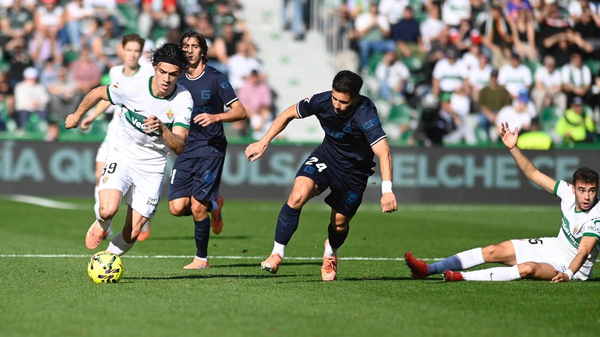 Héctor Fort conduce el balón mientras que Álvaro Núñez protesta desde el suelo.