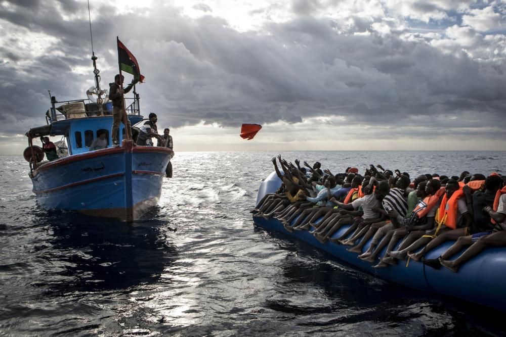 Pescadors libis llancen armilles salvavides a immigrants que viatgen a bord d'una embarcació en alta mar entre les costes de Líbia i Itàlia