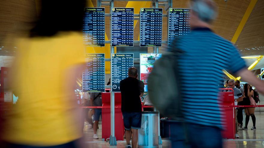 Imagen de archivo de varios pasajeros junto a paneles informativos de salidas en el Aeropuerto Adolfo Suárez Madrid-Barajas. EFE/Luca Piergiovanni