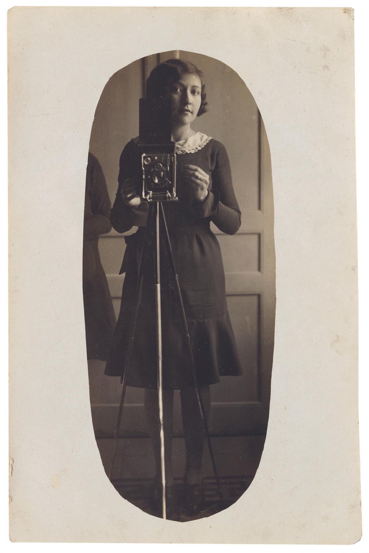 Autoretrat d’una noia amb càmera i trípode davant d’un mirall, c. 1929-1935