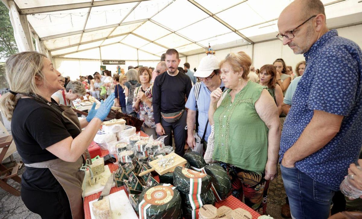 Mónica Fernández, atendiendo a varios clientes interesados en quesos del Cares. | Irma Collín.