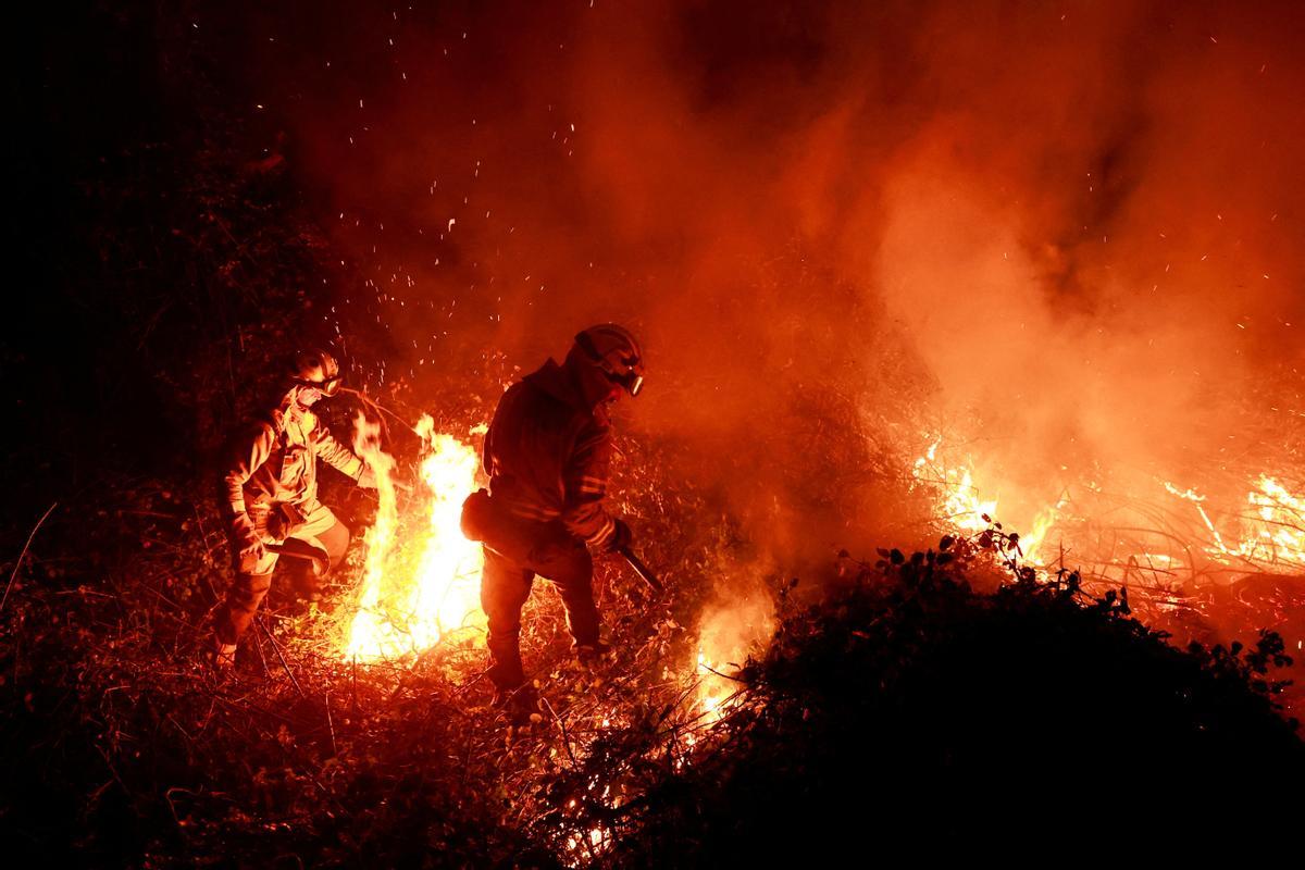 Un bombero gallego hace frente a las llamas en un bosque durante un brote de incendios forestales, en Piedrafita, Asturias