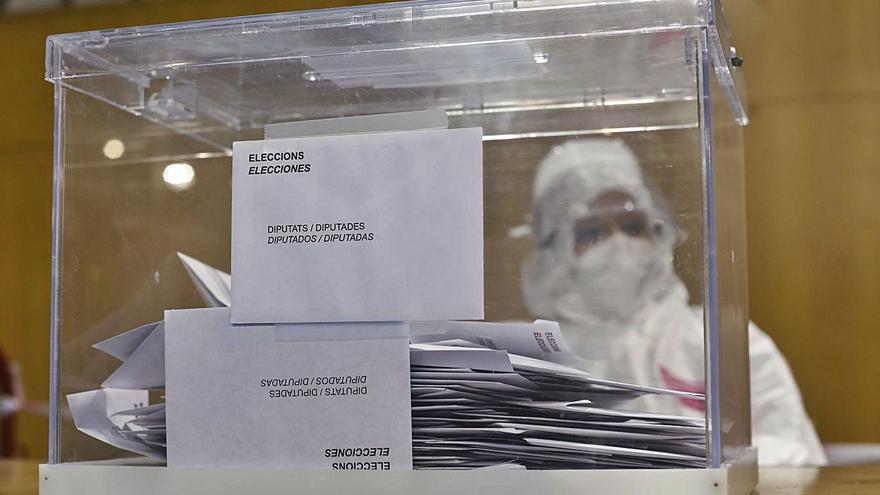 Un miembro de una mesa electoral aguarda la llegada de votantes, ataviado con un equipo de protección, durante las recientes elecciones catalanas.