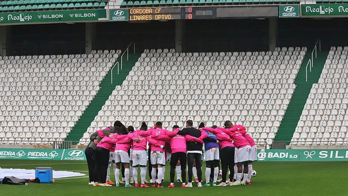 Los jugadores del Córdoba hacen una piña con la grada vacía antes de encuentro contra el Linares.