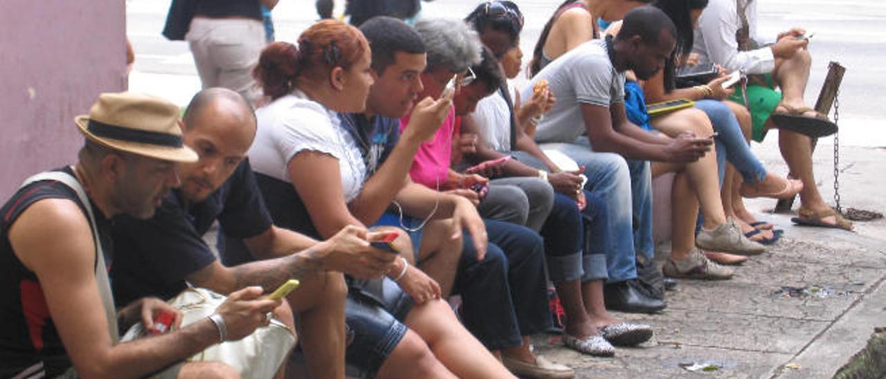 Jóvenes cubanos con distintas tecnologías captan señal wifi gratuita en las zonas de La Habana seleccionadas por el Gobierno. La prensa habanera las llama &quot;Wifilandia&quot;.