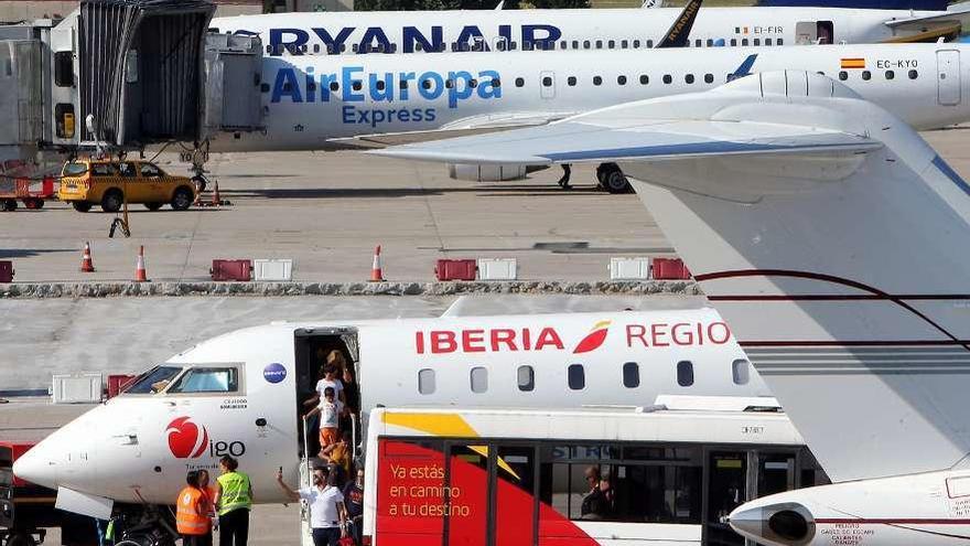 Pasajeros suben a un avión en Peinador en una jornada de trasiego en el aeropuerto. // Marta G. Brea