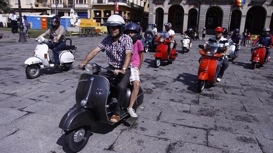 Participantes en la concentración de vespas recorren el casco antiguo de la ciudad.