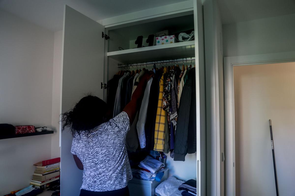 Una empleada de hogar organiza la ropa en un armario.