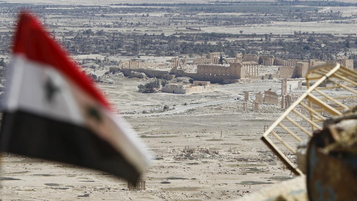 Una bandera siria ondea frente a las ruinas de la histórica ciudad de Palmira.