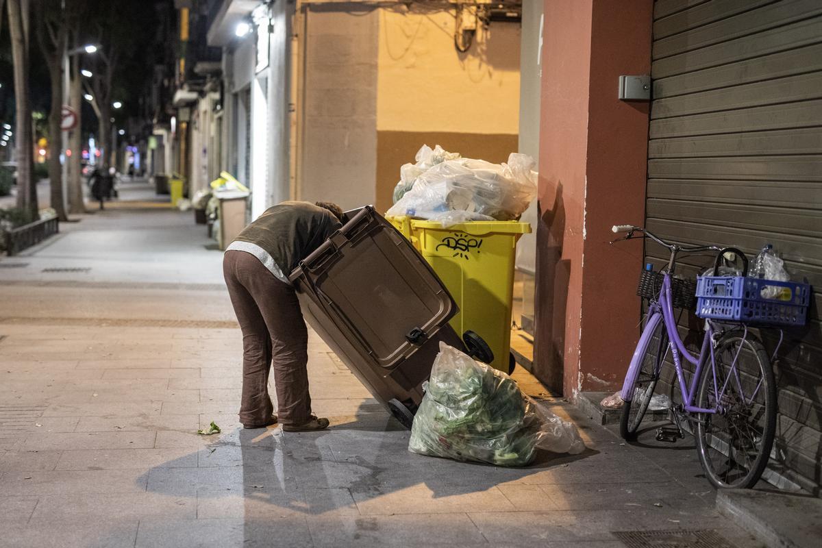 Un hombre rebusca en la basura en una calle próxima a Gran de Sant Andreu.