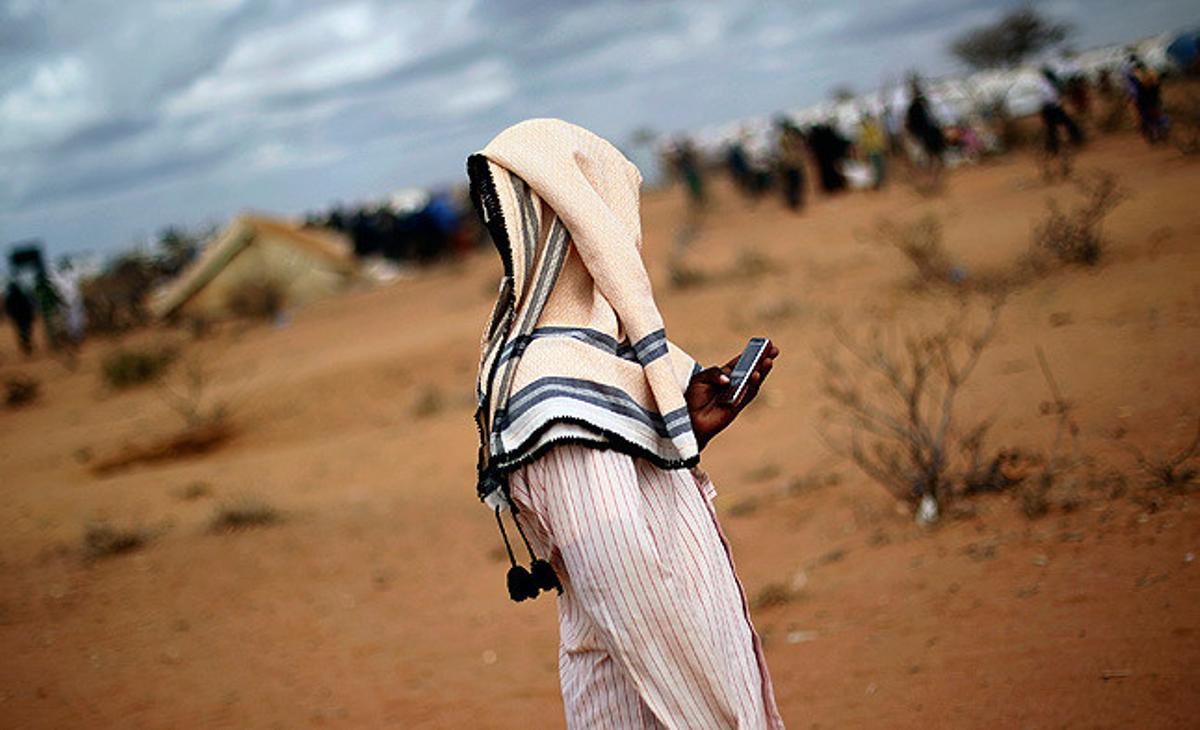 Un jove refugiat somali mira el seu mòbil en un camp de refugiats de l’ACNUR a Dadaab, a Kenya.