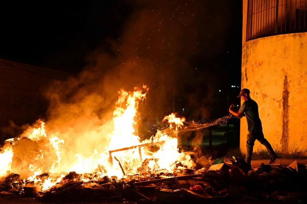 Un hombre lanza agua sobre un fuego encendido por manifestantes durante una protesta contra la falta de energía y los apagones en el barrio de Lawton, en La Habana, Cuba, el 14 de mayo de 2026. El gobierno cubano atribuyó a Estados Unidos la situación “particularmente tensa” de su red eléctrica, mientras el este del país sufrió otro corte generalizado ese mismo día. Washington ha ofrecido nuevamente 100 millones de dólares en ayuda, que el gobierno de la isla se muestra “dispuesto” a considerar.