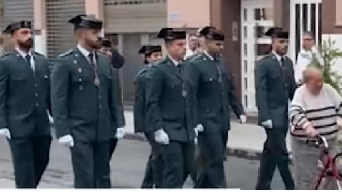 Momento en el que una señora cruza con su andador en una procesión de Elche cuando la Guardia Civil pasa por la calzada