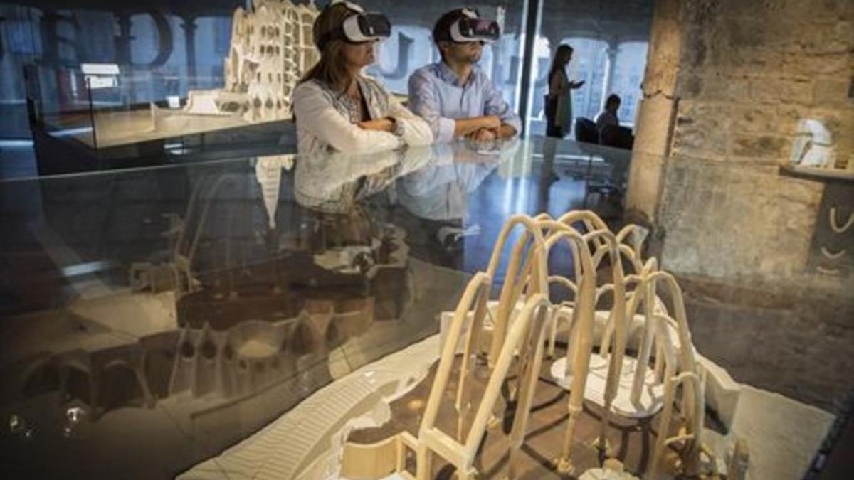 Dos visitantes ataviados con gafas de realidad virtual, en la exposición dedicada a Antoni Gaudí en el Museu Diocesà.
