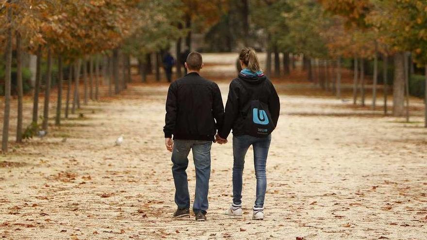 Una pareja camina de la mano por un parque.