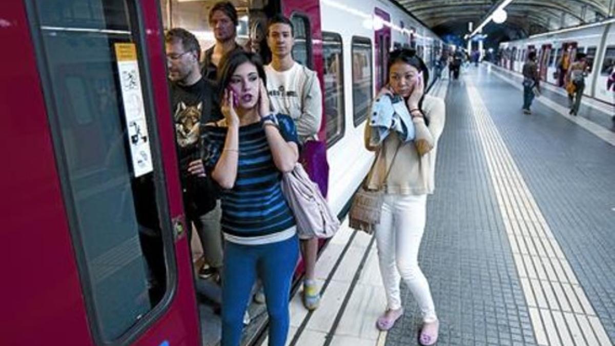 Varios viajeros de Ferrocarrils descienden de un tren parado en la estación de Plaça Catalunya, ayer.