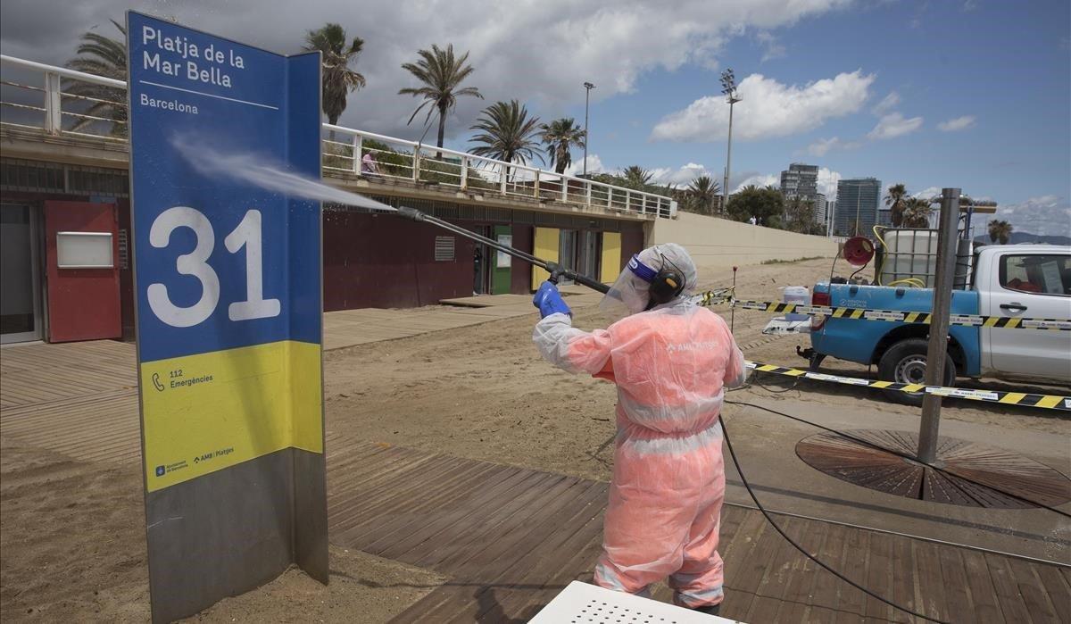 Operarios limpian las duchas y el mobiliario en la playa de la Mar Bella.