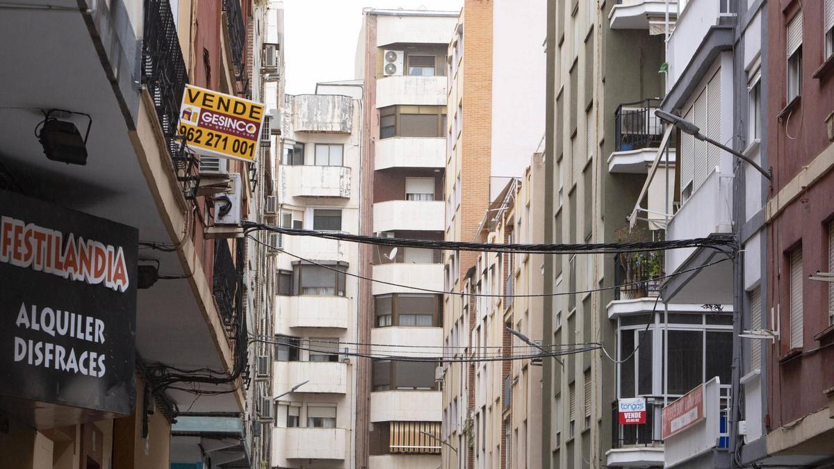 Edificios de pisos, algunos en venta, en una calle de Xàtiva.