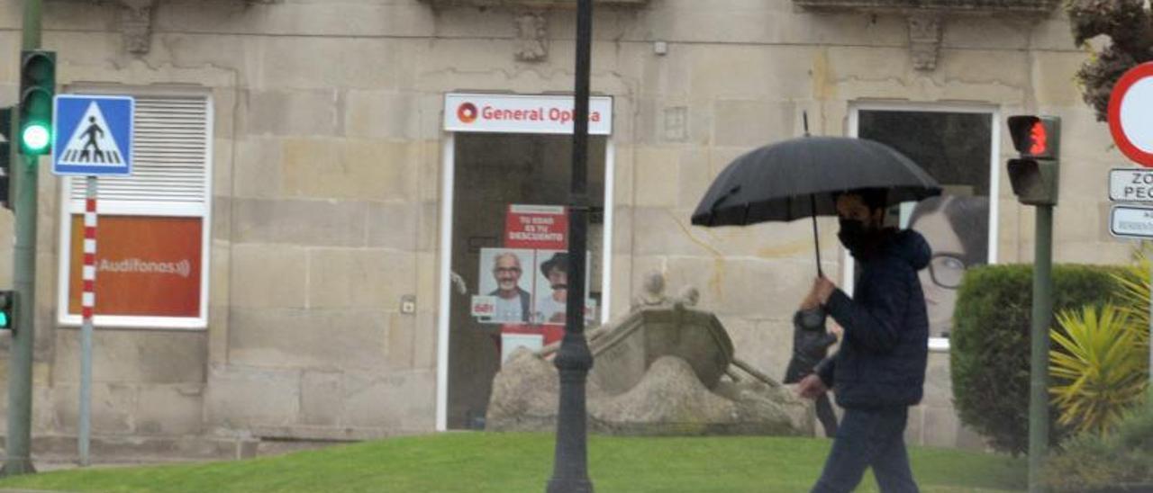 Un vecino se protege, ayer a mediodía, de la lluvia con un paraguas en el centro de Cangas. |   // GONZALO NÚÑEZ