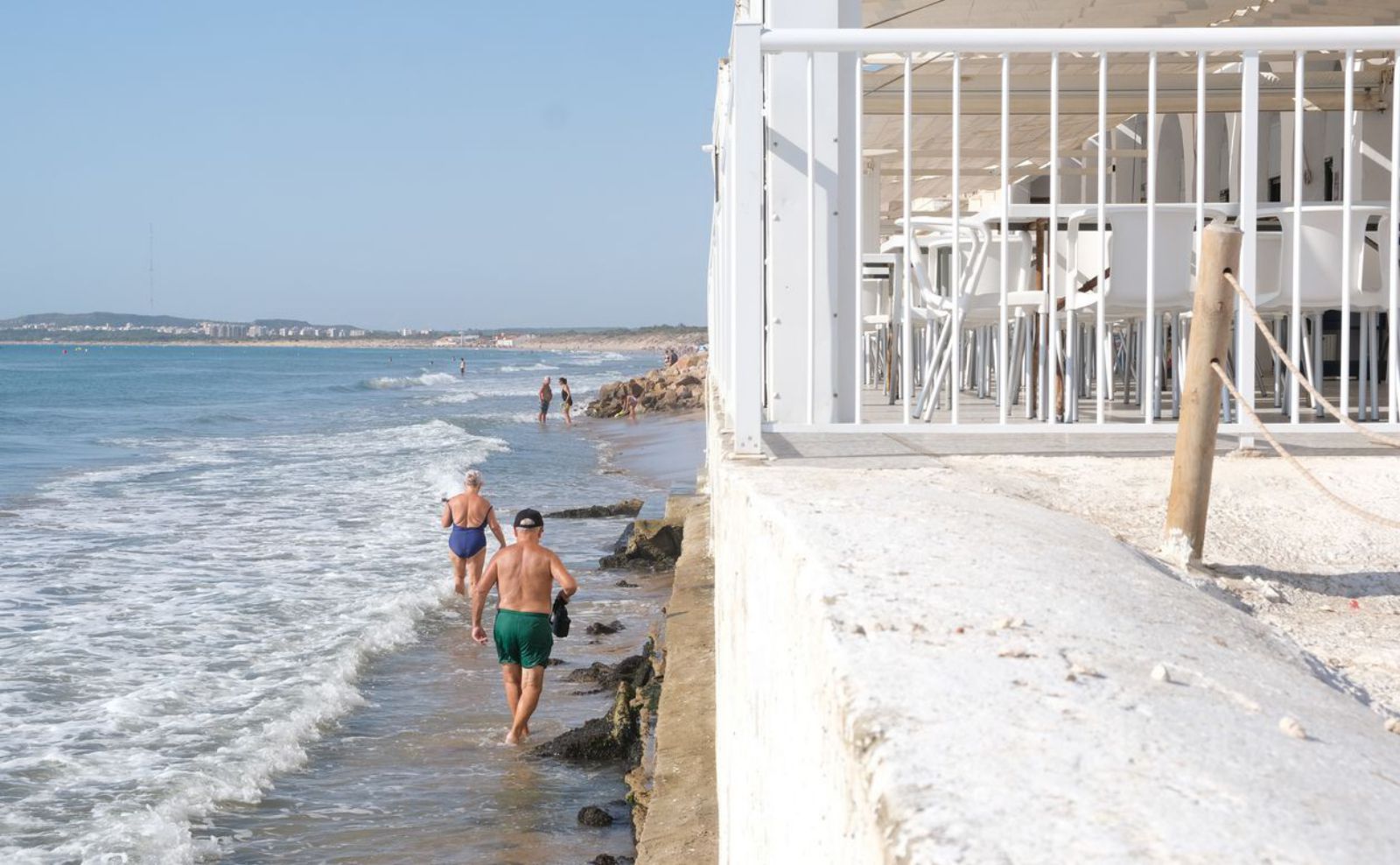 Unos bañistas pasan por la playa de El Pinet. 