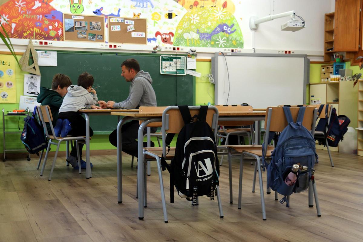 Dos alumnes escolten les explicacions del docent, en una imatge de recurs.
