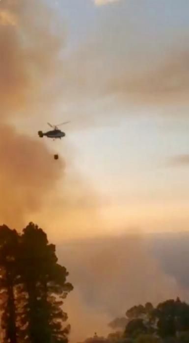 A firefighting helicopter is seen as wildfire ...