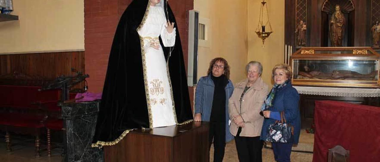 Por la izquierda, Nides Berdasco, Rosi Menéndez y Pilar Meana posan junto a la imagen de la Virgen de la Soledad con su nuevo atuendo, ayer, en la iglesia de Lugones.