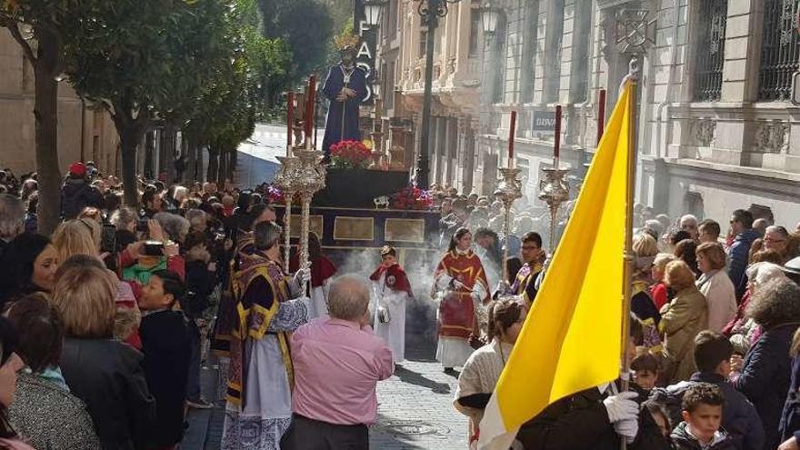 Arriba, varias personas acompañando la solemne salida en la calle San Francisco. En el centro, la banda de la Hermandad y, a la izquierda, mujeres con mantilla española.