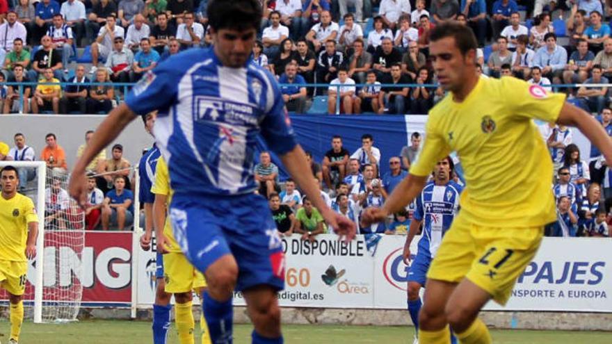 El delantero Rafa Gómez conduce el balón perseguido por el lateral del Villarreal B Pere.