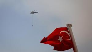 Archivo - Imagen de archivo de un helicóptero de los Bomberos detrás de una bandera de Turquía