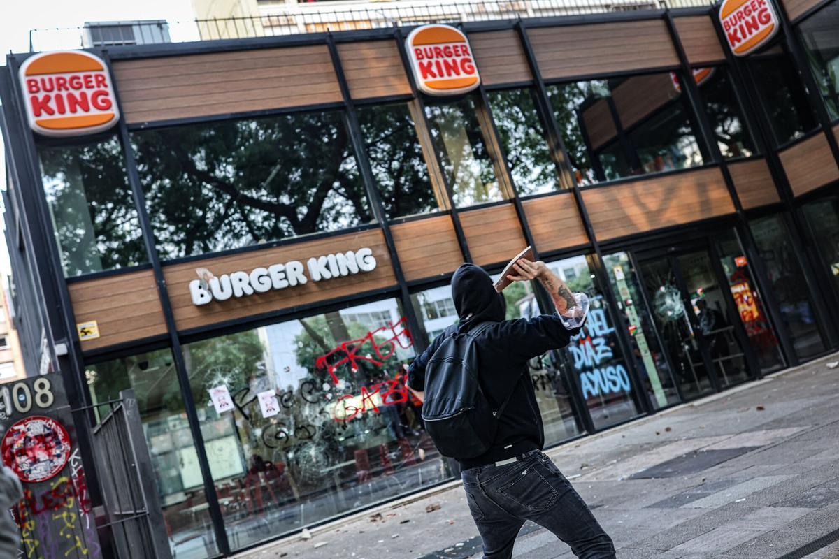 Una persona a punt de llançar un objecte a una cadena de menjar ràpid durant una manifestació pro Palestina a Barcelona