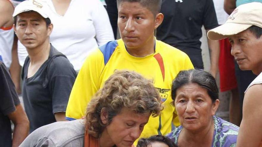 Una mujer es sujetada mientras llora desconsolada en plena calle.