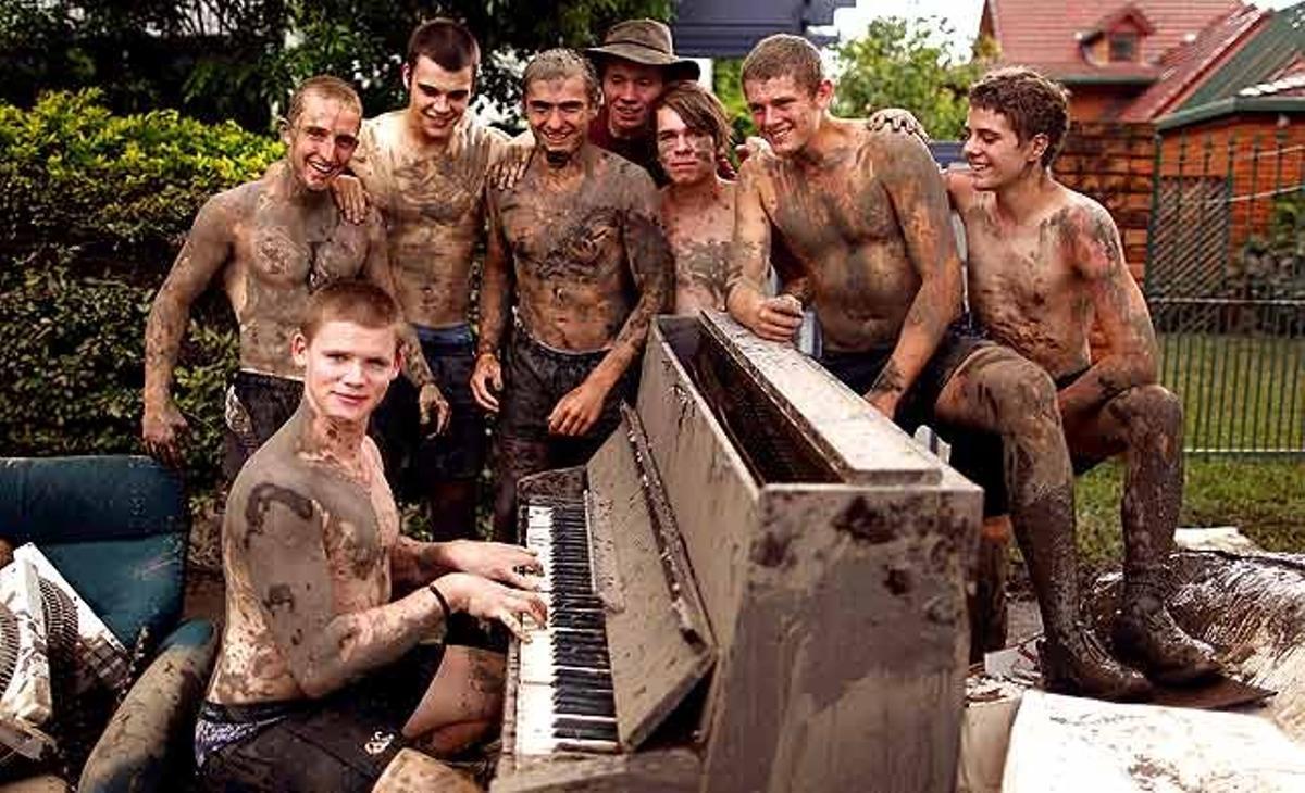 Andrew Taylor (segon per la dreta) i els seus amics, coberts de fang, posen al voltant d’un piano destruït mentre ajuden la família de Taylor a netejar casa seva després que les pluges inundessin el suburbi de Brisbane de Westend (Austràlia).