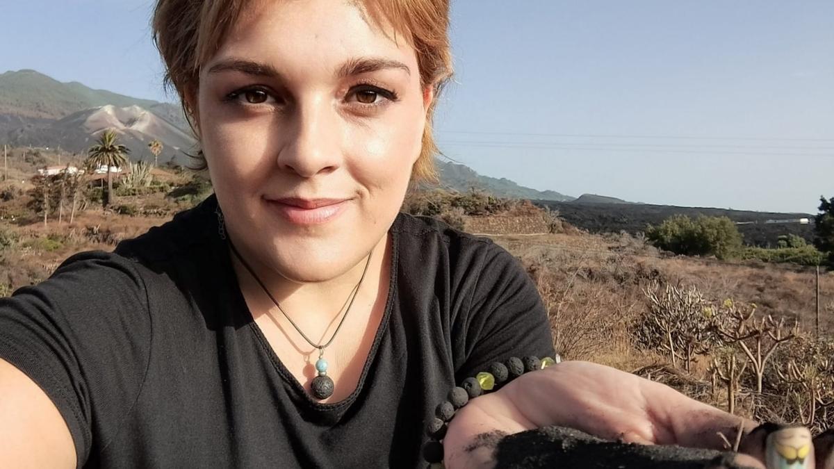 Gloria Martín en la isla de La Palma, con el volcán Cumbre Vieja detrás y en su mano cenizas de su última erupción, durante las vacaciones que pasa estos días en ese lugar.