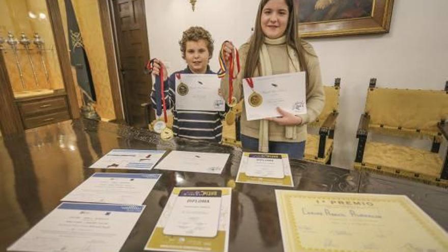 Los hermanos Aracil posan orgullosos, en la sala del Oriol, con algunas de sus medallas y diplomas.