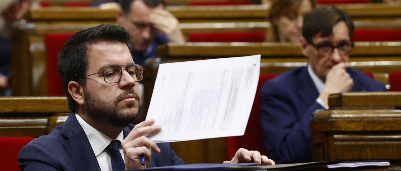 Salvador Illa, al fons, observa Pere Aragonès, ahir al Parlament.  | QUIQUE GARCÍA / EFE