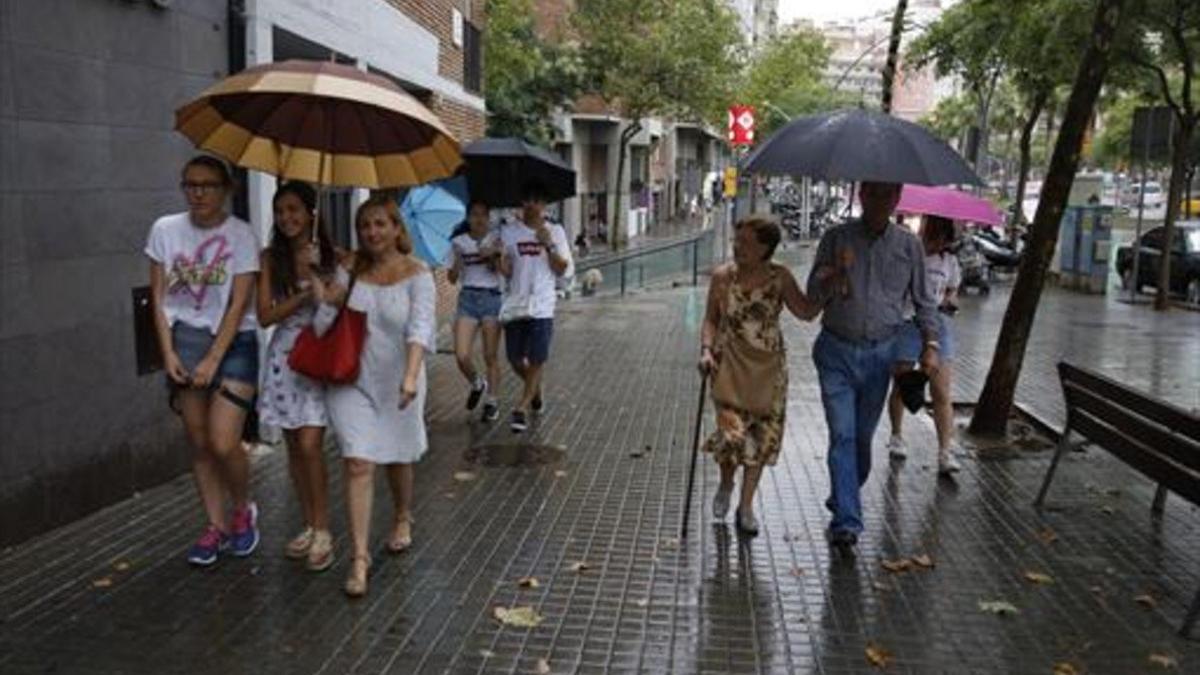 Transeúntes con paraguas en la tarde de ayer, en la Ronda de Guinardó de Barcelona.