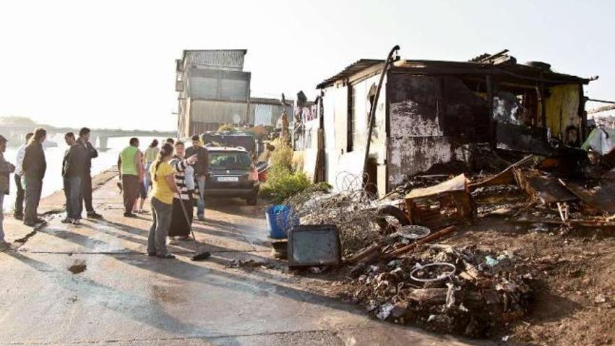 Un grupo de habitantes del poblado, ante la chabola destruida por las llamas. / 13fotos