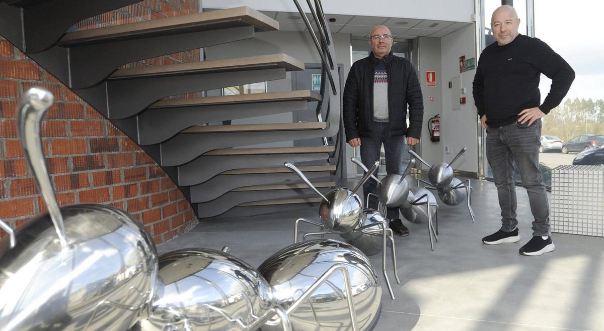 Jose Luis y Javier Campos posan a la entrada de su fábrica en el polígono de Toedo, junto a esculturas metálicas de hormigas. | BERNABÉ/JAVIER LALÍN