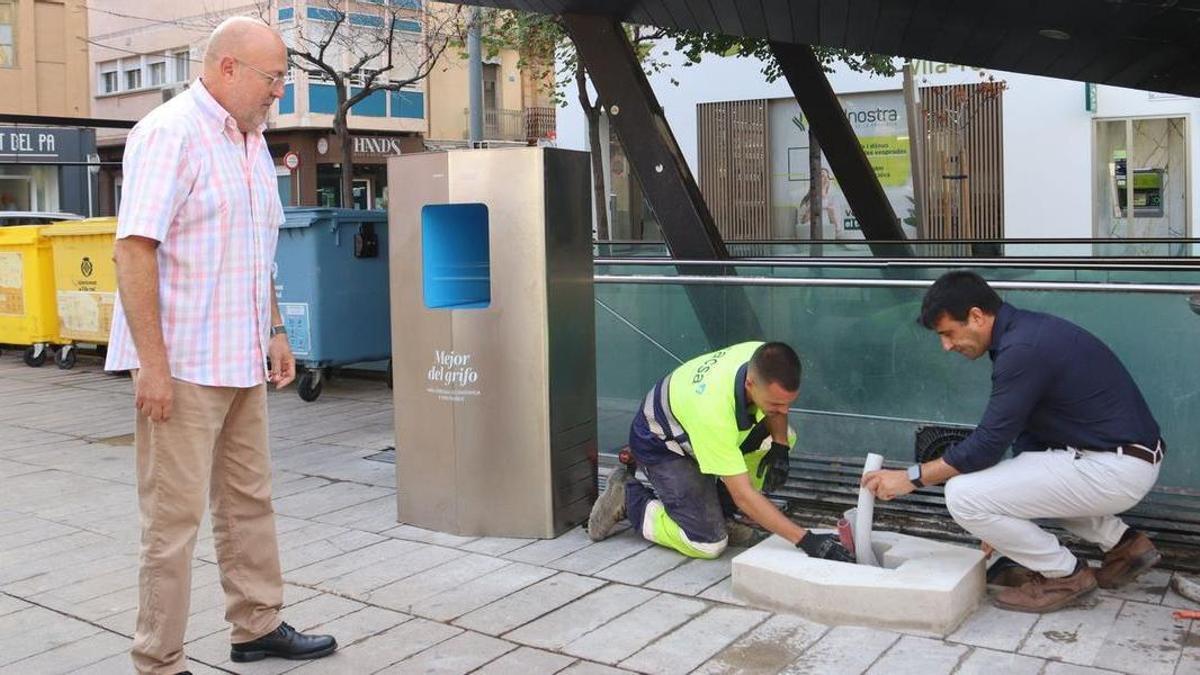 El concejal Obiol supervisa los trabajos de instalación de la fuente de agua refrigerada que se instala en la plaza Major y que se prevé que esté operativa para las fiestas de la Mare de Déu de Gràcia.