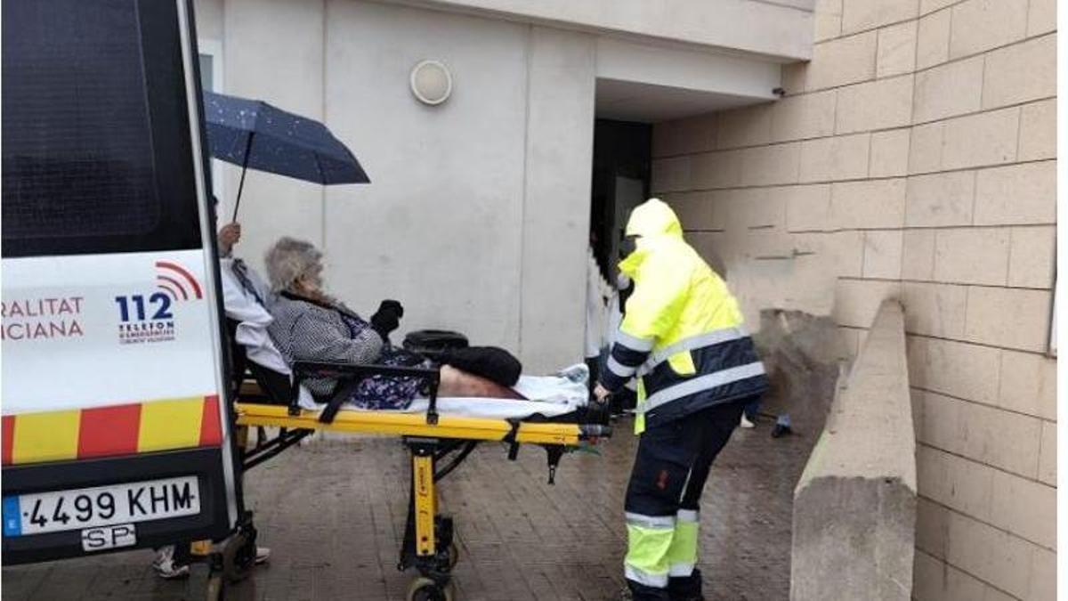 Un familiar protege a una paciente con un paraguas, ayer, en el acceso al hospital por la zona de las ambulancias.