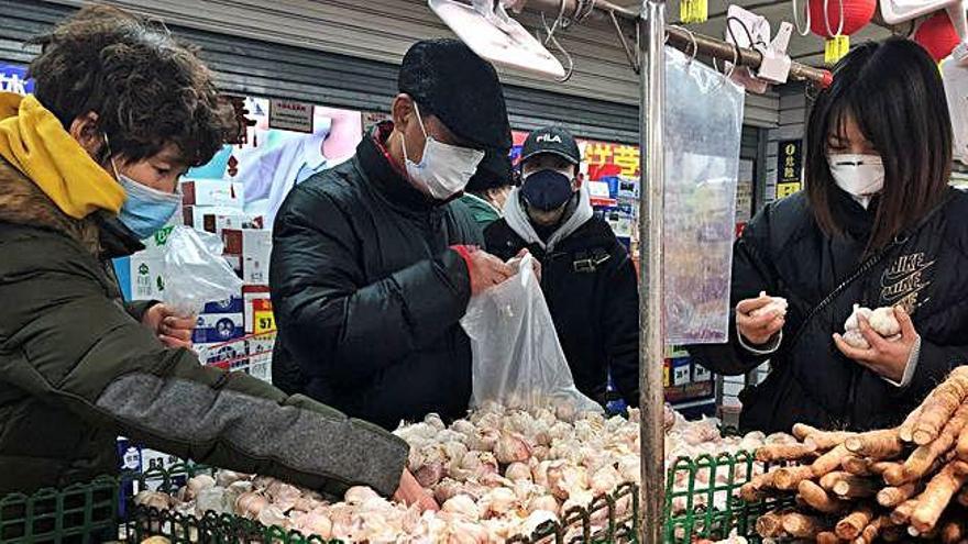 Quatre persones compren fruita en un mercat amb les màscares posades a Pequín, la capital de la Xina