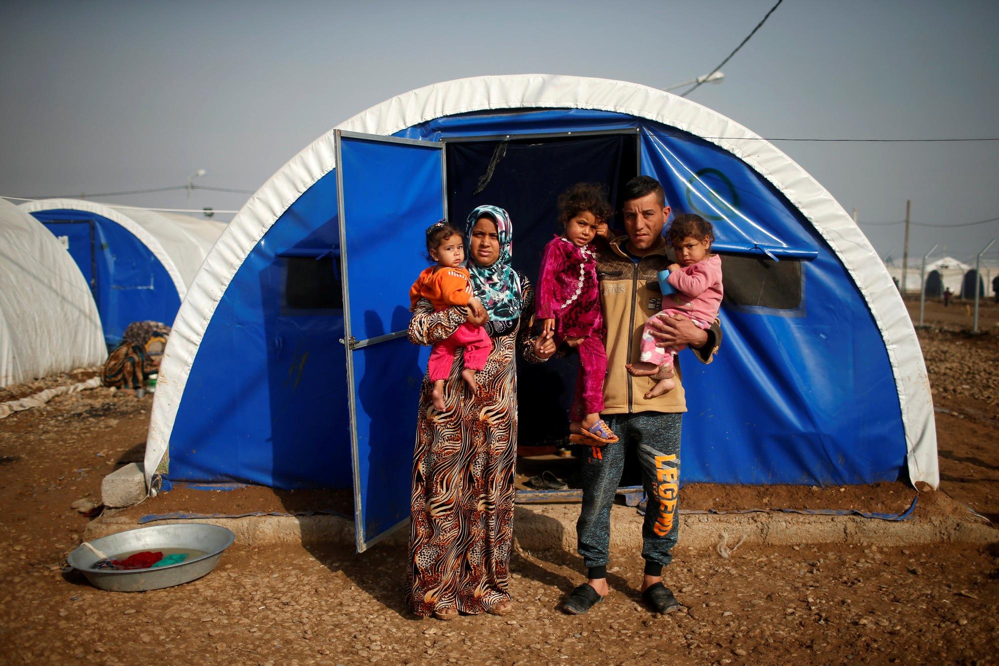 The Wider Image: Mosul displaced find refuge in camp Displaced Iraqi Amjad Galadi, 20, poses for a photograph with his wife and children at Hammam al-Alil camp south of Mosul, Iraq, March 29, 2017. Galadi and his wife, who got married three years ago, were anxious to save the children from shelling and air strikes. Galadi remembered covering his children's eyes as they escaped. The children are one, two and three years old. REUTERS/Suhaib Salem