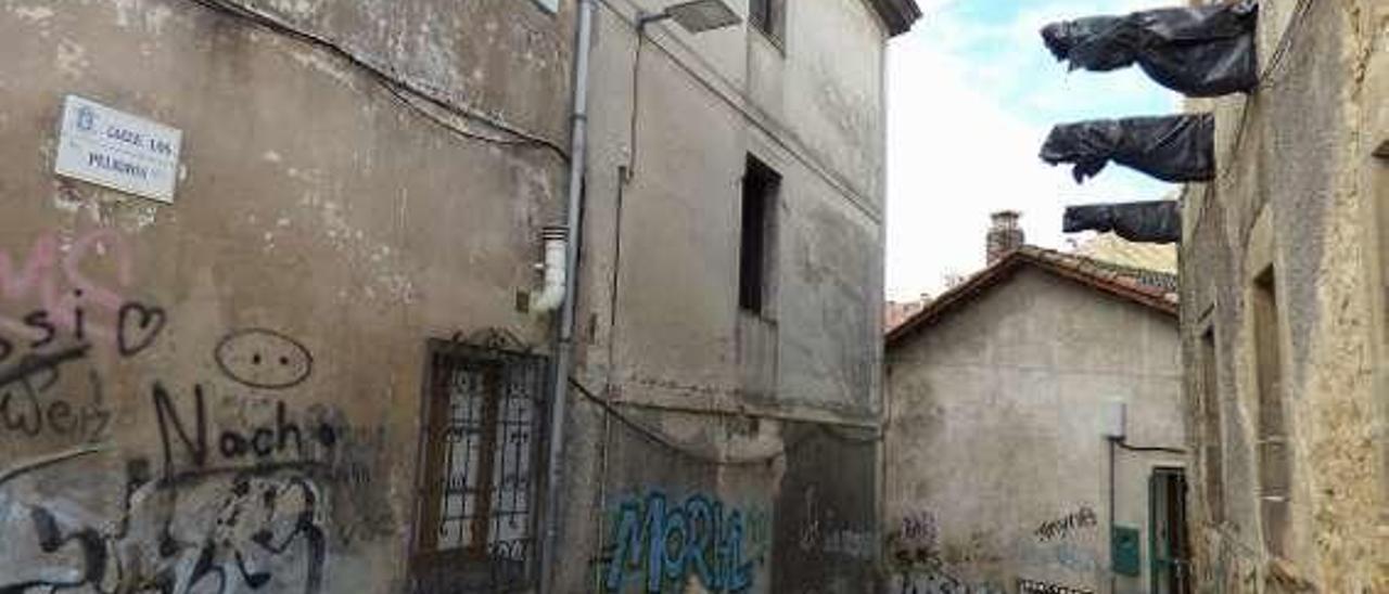 Un sillón abandonado en plena calle de los Peligros, con varios edificios vacíos y en ruina.