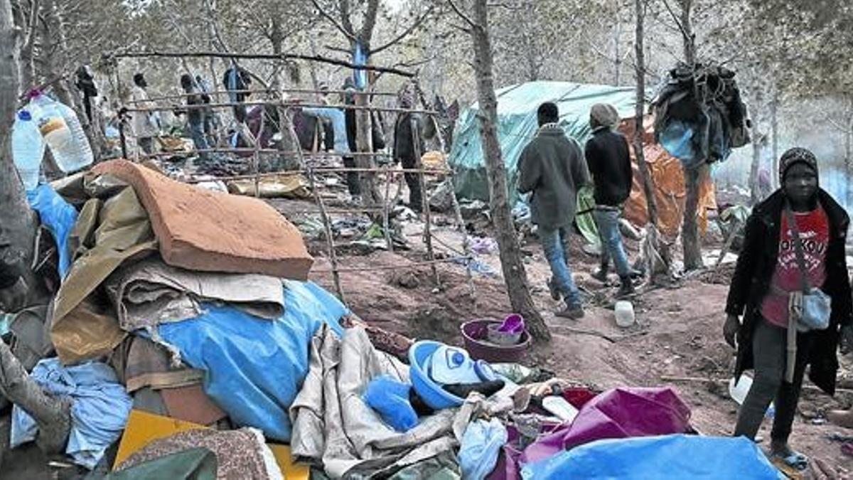 Subsaharianos recogen los restos de sus pertenencias después de la redada de la policía marroquí en su campamento, cerca de Nador.
