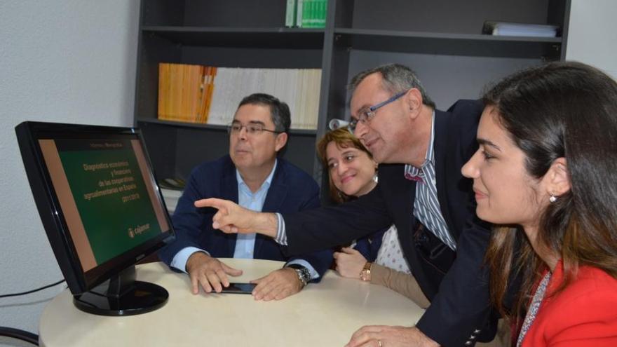 Arcas señala la portada del libro en una pantalla de ordenador junto a su equipo de trabajo.