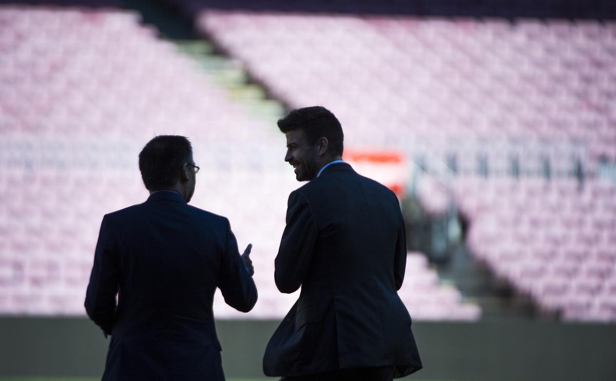 Las siluetas de Gerard Piqué junto al presidente Josep Maria Bartomeu sobre el terreno de juego del Camp Nou durante el acto de renovación del jugador por el club azulgrana hasta el año 2022.